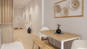 A modern, well-lit room with a wooden dining table, white chairs, and a bench. There is a small white cabinet with decorative items and a mirror on the wall. - The Sea Rooms I | AC & WIFI | 15 min Beach (Valencia)