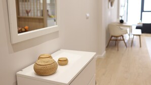 A modern interior with a white console table displaying woven baskets, a large mirror, and a view of a dining area with a chair and table. - The Sea Rooms I | AC & WIFI | 15 min Beach (Valencia)