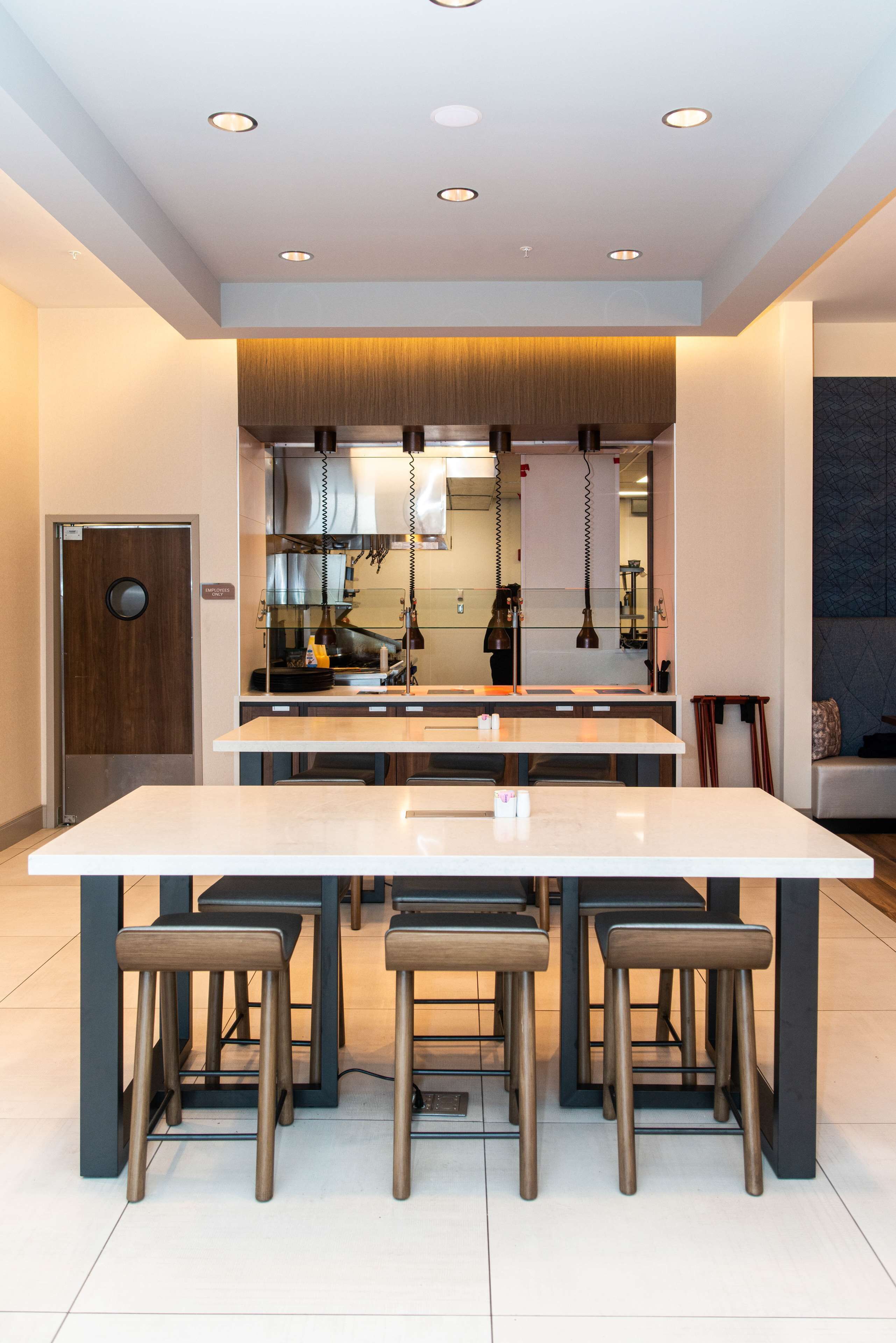 Een moderne keuken met een centraal eiland, barkrukken en inbouwspots.