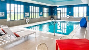 Ein Hallenbad mit deutlich sichtbaren Regeln, einem Rettungsschwimmerstuhl und einem roten Tisch.