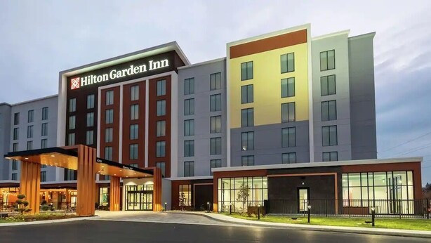 Ein Hilton Garden Inn mit modernem Design, das einen markanten Eingangsbereich und mehrere Stockwerke zeigt.