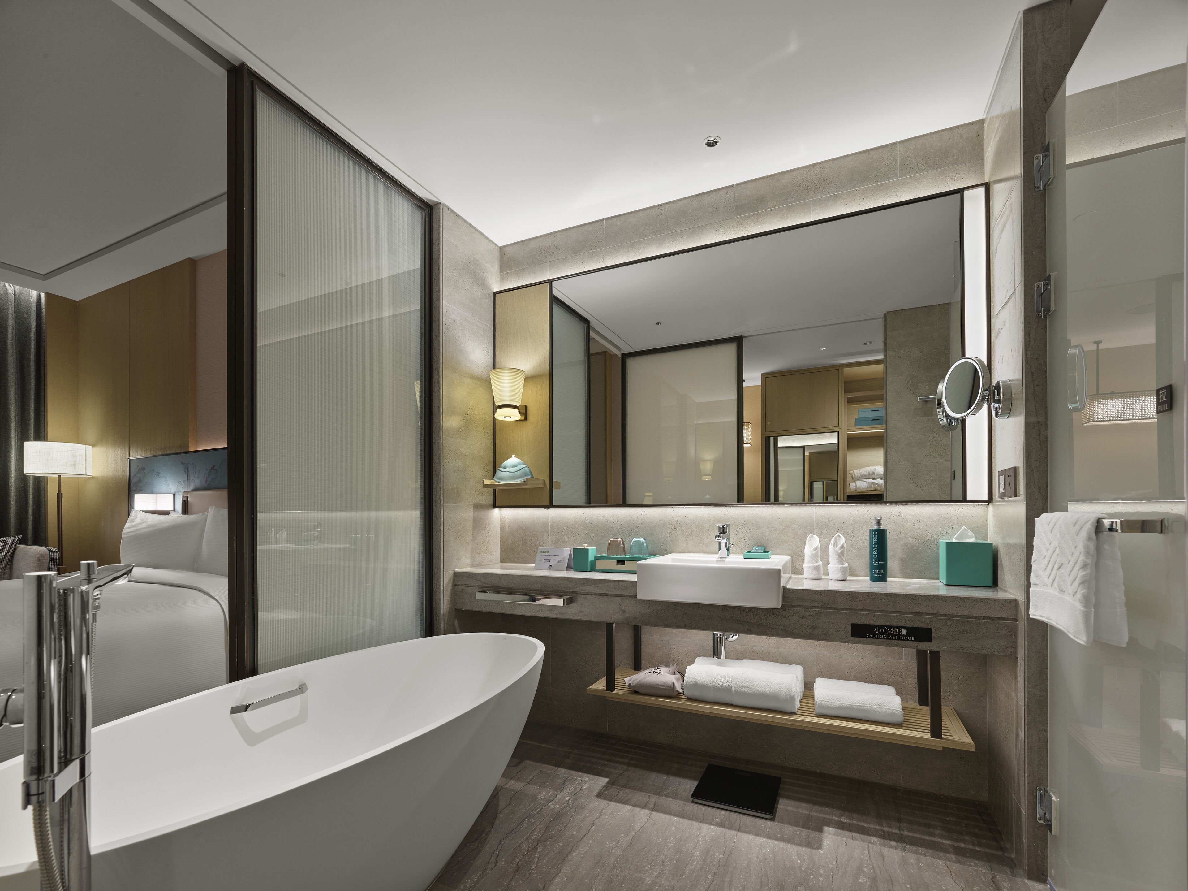 A modern bathroom with a freestanding bathtub, a vanity with a mirror, and a towel rack.