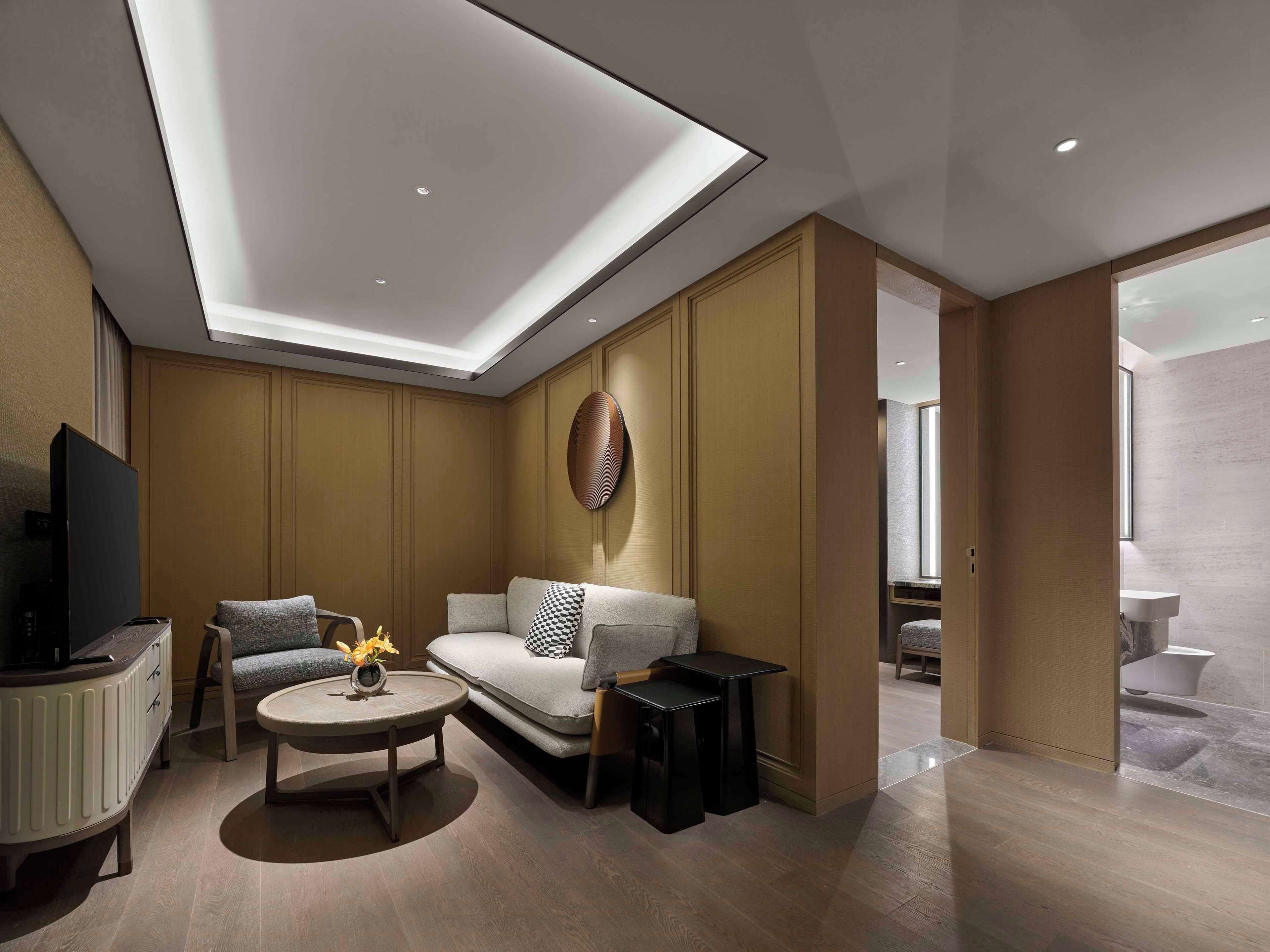 A modern living room with a sofa, armchairs, a coffee table, and a TV.