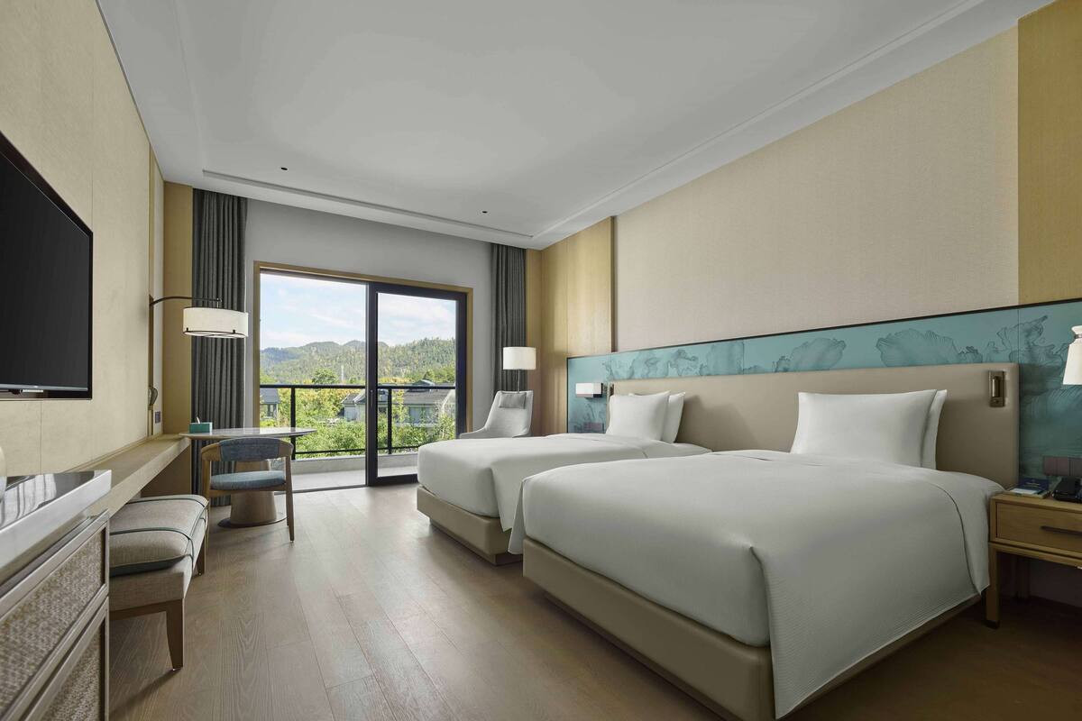 Een hotelkamer met twee bedden, een bureau, een stoel en een televisie.