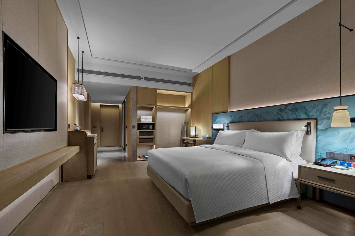 Een moderne hotelkamer met een groot bed, nachtkastjes, een flatscreen-tv en een inloopkast.