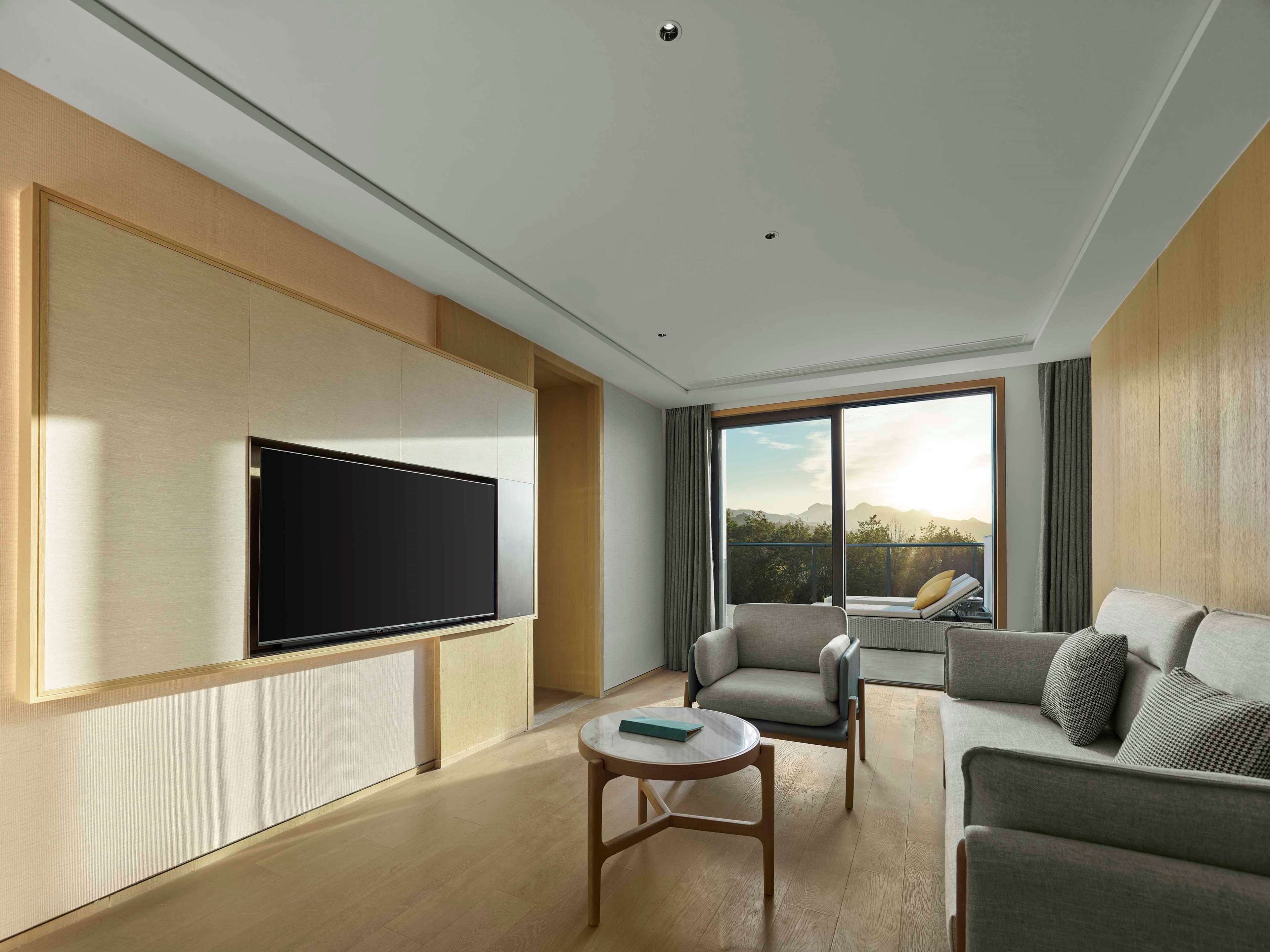 Una sala de estar moderna con un televisor de pantalla plana montado en la pared, un sofá, un sillón y una mesita.