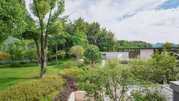 A modern building with a flat roof, surrounded by a well-maintained garden with various trees and shrubs.