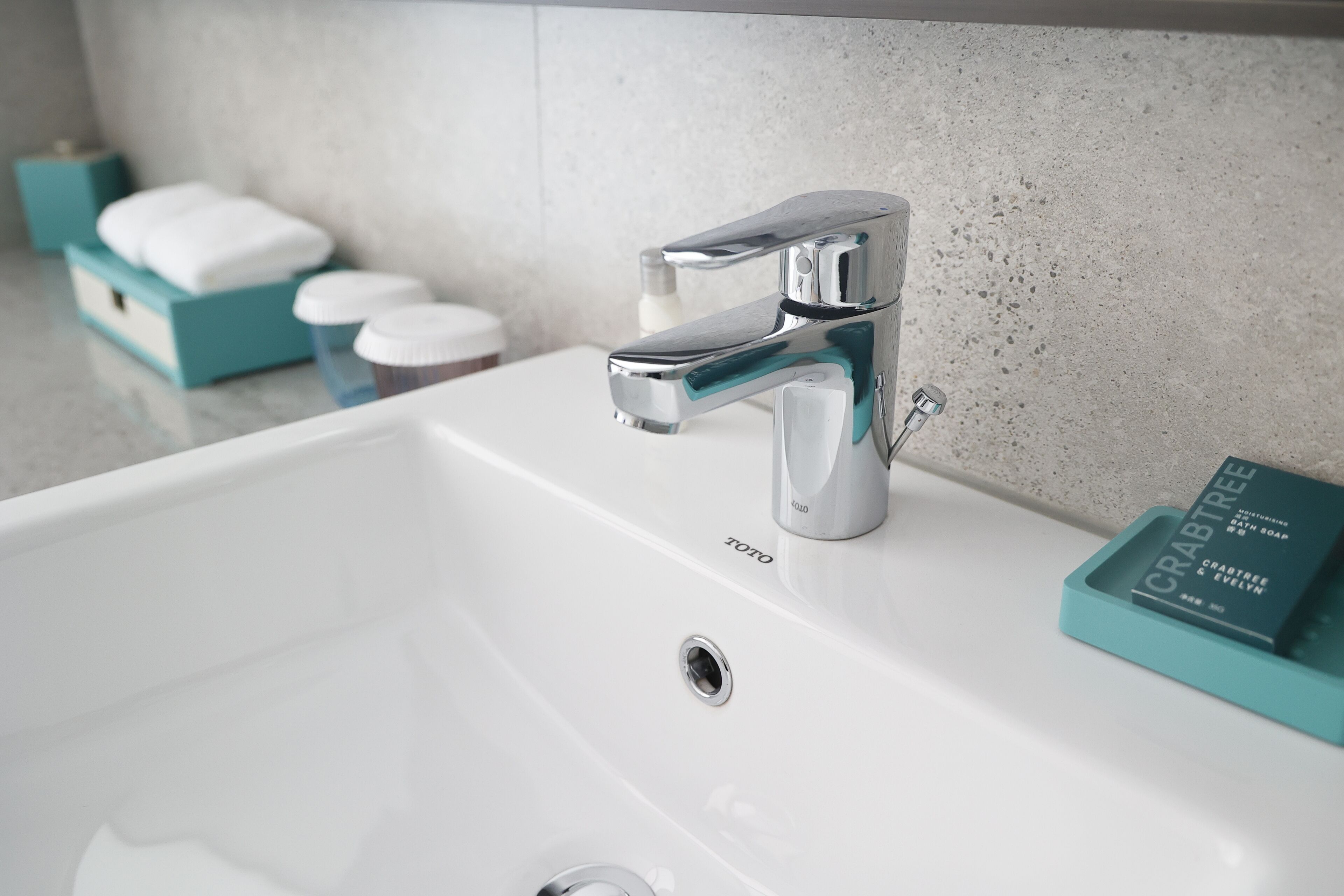 Ein modernes Badezimmer mit Armatur aus Chrom, einem weißen Waschbecken und einer blauen Seifenschale.