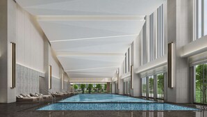 Una amplia piscina cubierta con suelo de baldosas, rodeada de paredes con un diseño texturizado y grandes ventanales.