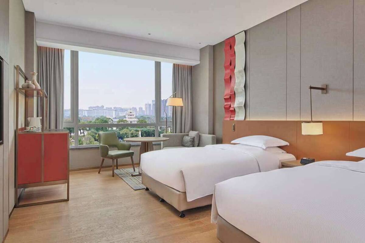 Une chambre d’hôtel avec deux lits, un bureau, une chaise et une vue sur la ville.