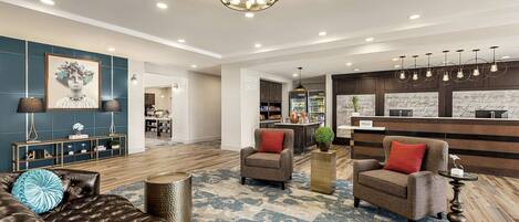 A hotel lobby with a seating area, a reception desk, and a minibar.