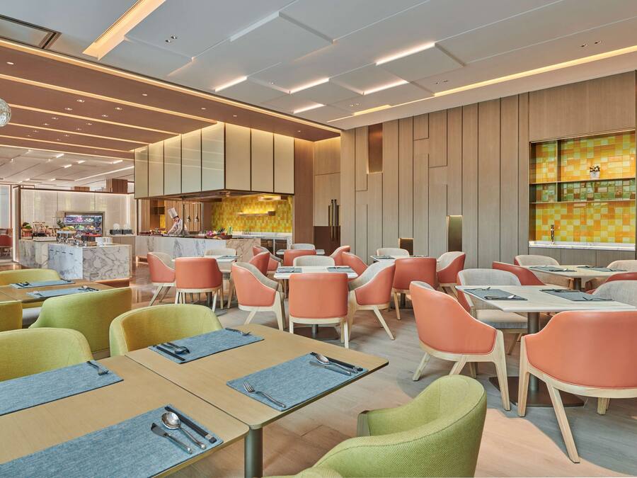 Un restaurante moderno con diversas opciones de asientos, como mesas y sillas, y una cocina visible al fondo.