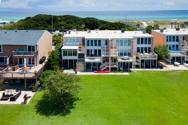A beachfront hotel with multiple balconies, outdoor seating, and a view of the ocean.