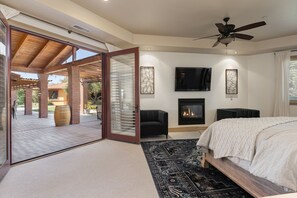 A modern bedroom with a large bed, a fireplace, and a TV.