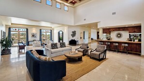A spacious living area with a high ceiling, a kitchen with wooden cabinets, and a bar area. - Dresser Winery Estate Villa - Pool, Hot Tub, Sauna on a Vineyard! 10 min to town (Paso Robles)