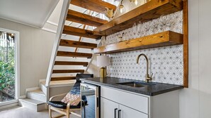 A modern kitchen with a built-in stove, a sink, and a wooden staircase. - Stylish Modern 6 Bdrm + Hot Tub + Pool Access (Gatlinburg)
