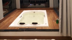 Une chambre dotée d’une grande fenêtre, d’un jacuzzi et offrant une vue sur le paysage urbain.