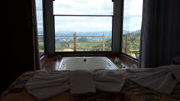 Une salle de bain avec une baignoire, des serviettes et une vue sur les montagnes, visible à travers de grandes fenêtres.