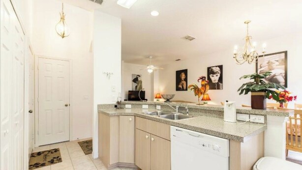 A modern kitchen with granite countertops, a dishwasher, and a sink. There are decorative items on the counter and a plant on the right. - 💖20 mins 2 Disney; 400Mbps WiFi; 2 Masters✔️Gated (Kissimmee)