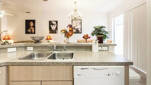 A modern kitchen with granite countertops, stainless steel sinks, a dishwasher, and a chandelier. - 💖20 mins 2 Disney; 400Mbps WiFi; 2 Masters✔️Gated (Kissimmee)