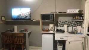 A compact kitchen with a television, a refrigerator, a microwave, and a coffee maker. - Comfort Breeze Studio (Nassau)