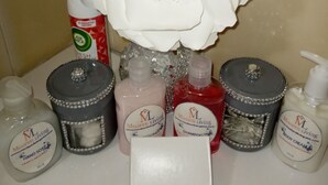 A bathroom vanity with a white sink, a mirror, and various toiletries including hand soap, shampoo, and body cream. - Comfort Breeze Studio (Nassau)