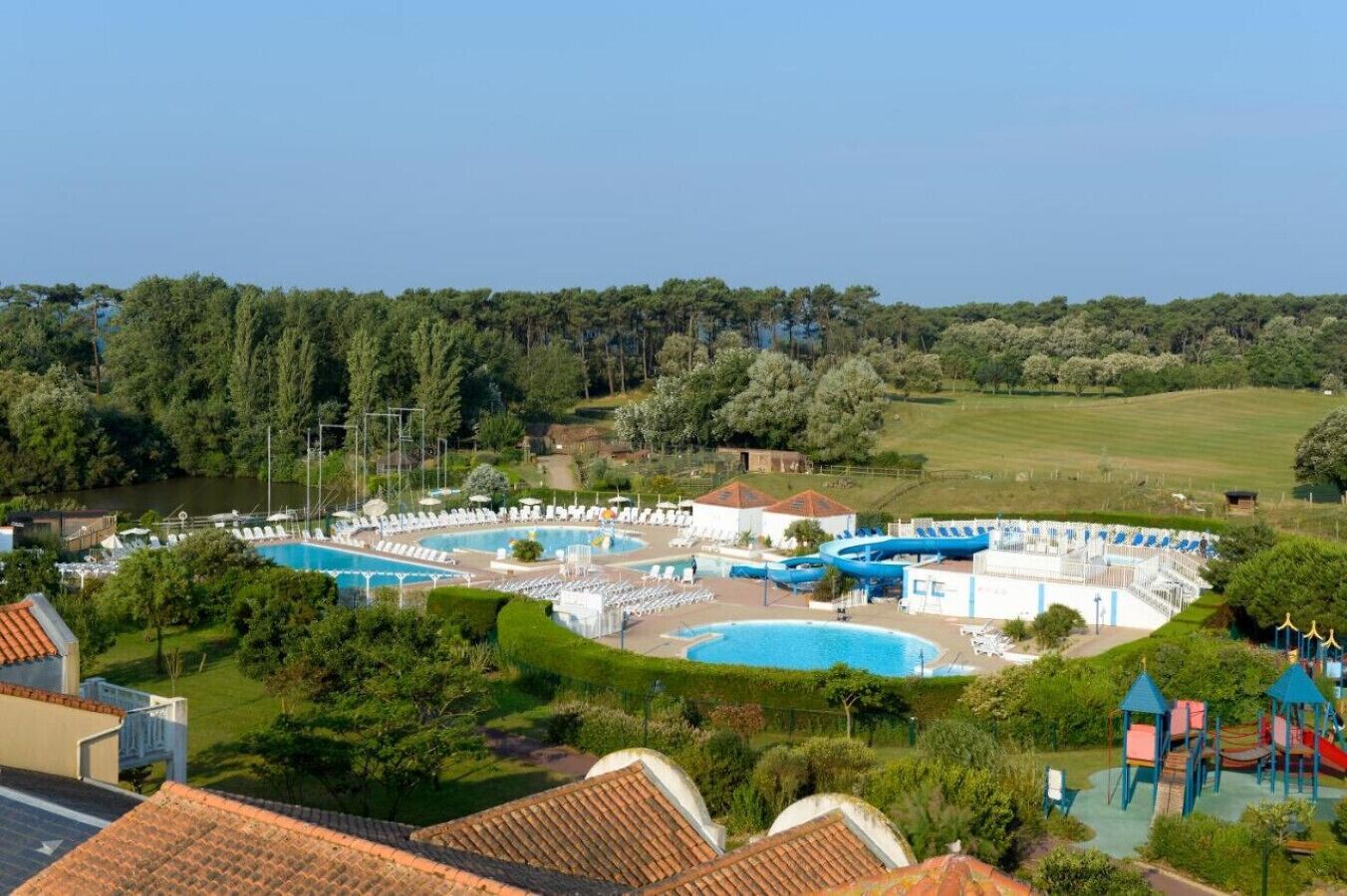 A resort with multiple swimming pools, a children's play area, and lush greenery.