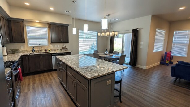 A modern kitchen with granite countertops, dark wooden cabinets, and a central island. - Modern 3BR Hildale Oasis near Zion, King Bed & Balcony, Massive Cliff Views! (Hildale)
