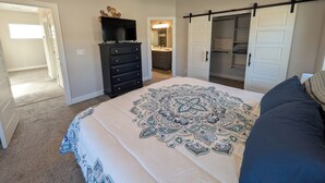 A bedroom with a bed, a dresser, a television on top, a ceiling fan, and a walk-in closet. - Modern 3BR Hildale Oasis near Zion, King Bed & Balcony, Massive Cliff Views! (Hildale)