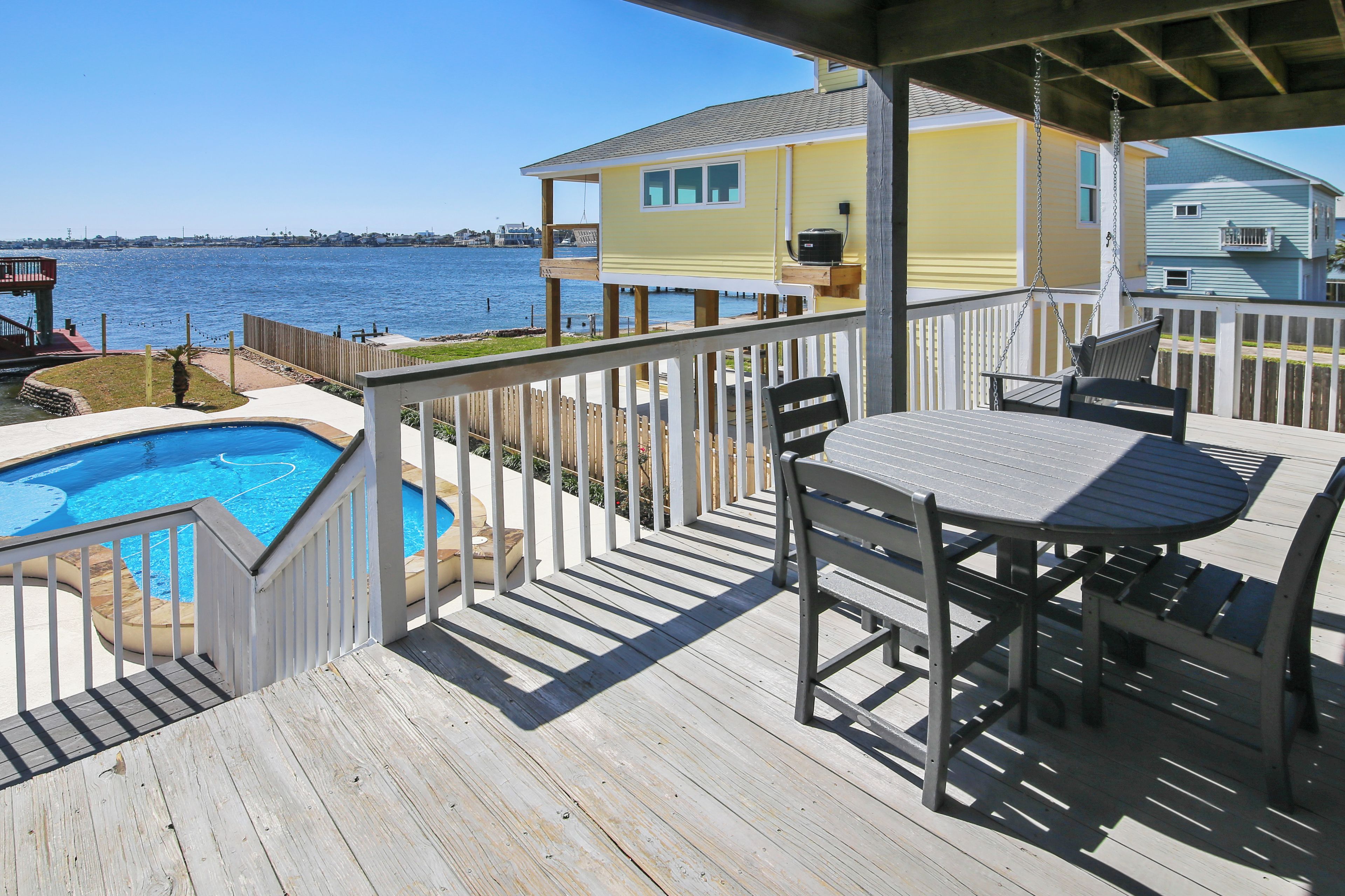 A wooden deck with a pool, outdoor furniture, and a view of the water.