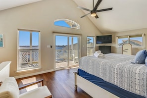 A bedroom with a large bed, a ceiling fan, and a view of the outdoors through a sliding door. - Pool Days and Dock Nights by Ryson Vacation Rentals (Galveston)