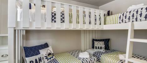 Habitación con literas, dos camas, cada una con ropa de cama y almohadas estampadas.