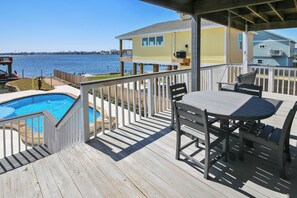 A wooden deck with a pool, outdoor furniture, and a view of the water.