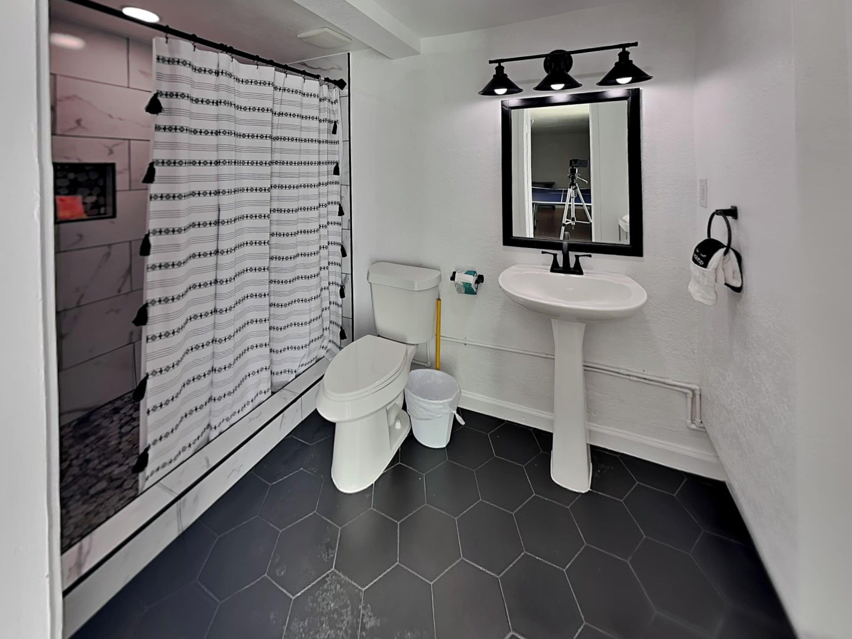 A bathroom with a shower, toilet, sink, and mirror.