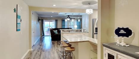 Una cocina moderna con barra, suelo de madera y un cartel que dice 'HAPPY HOUR'.