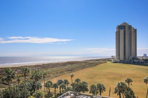 A high-rise hotel overlooking a beach with a clear view of the ocean.