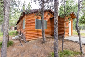 A log cabin with a small porch, a door, and a window.