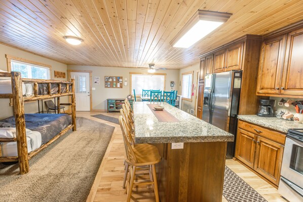 A kitchen with wooden cabinets, a granite countertop, and a stainless steel refrigerator.
