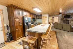 A spacious kitchen with wooden cabinets, a granite countertop, and a built-in island with bar stools.