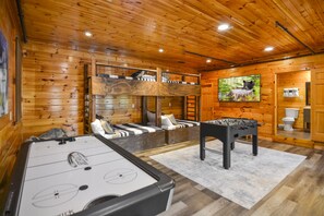 A cozy wooden cabin with a foosball table, a bunk bed, and a television.