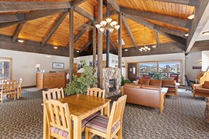 A spacious interior with a high wooden ceiling, a stone fireplace, and a view through large windows.