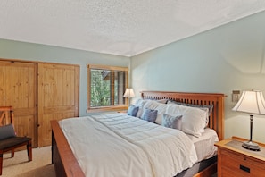 Cozy retreat with a large bed, wooden nightstand, and comfortable chair.