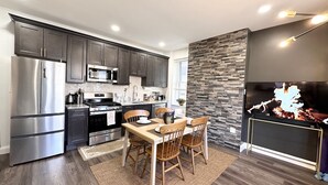 A modern kitchen with stainless steel appliances, a herringbone tile backsplash, and a stone accent wall. - Cozy 2 bdrm Unit/Big Kitchen-2 TV- University City (Philadelphia)