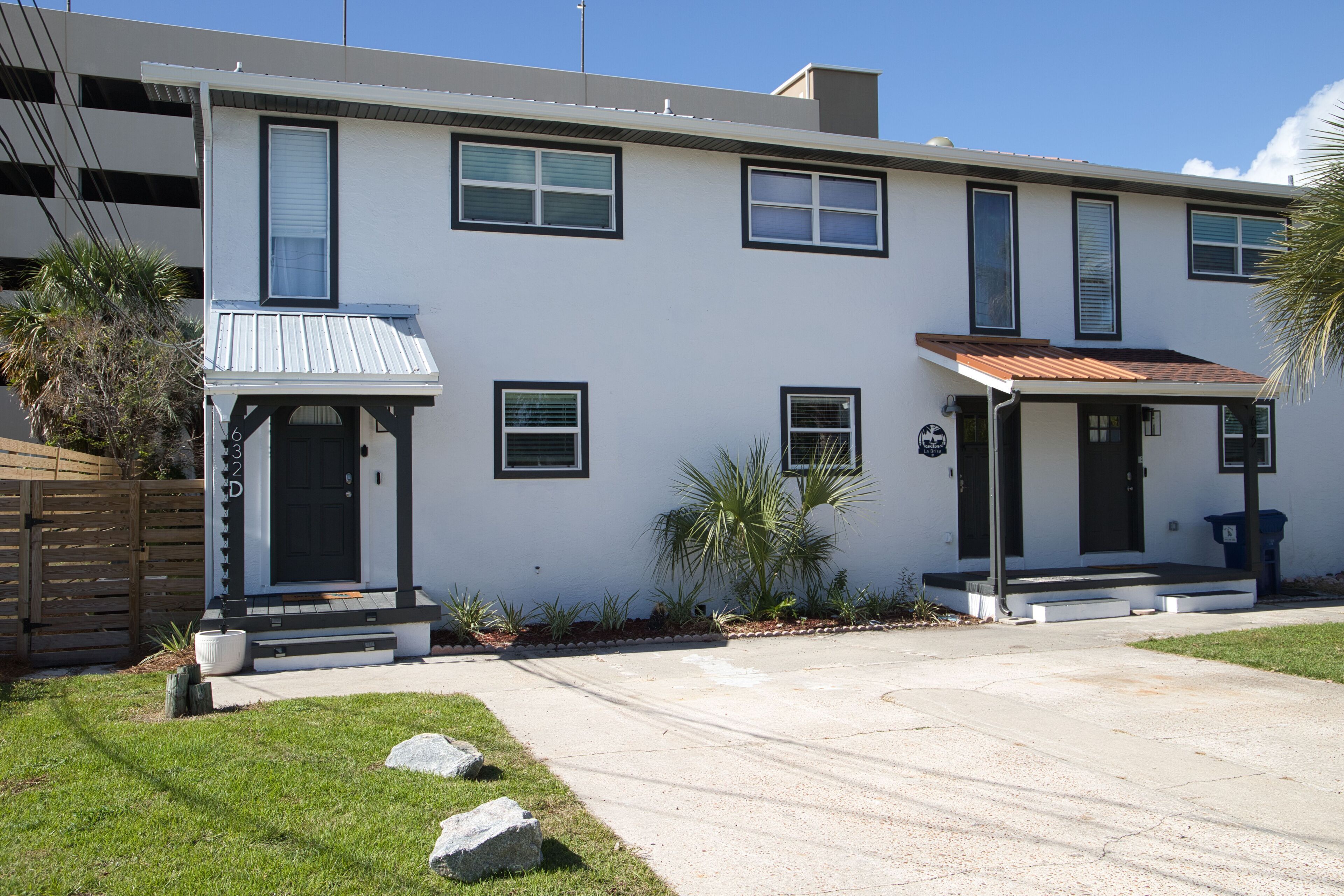 A modern two-story house with a front porch, a small garden, and a driveway.