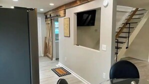 A modern interior with a staircase, a glass table, and a door leading to another room.