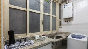 A kitchen with a granite countertop, a sink, a window with frosted glass, and a water heater. - 2 Minutes From Copacabana Beach A303 (Rio de Janeiro)