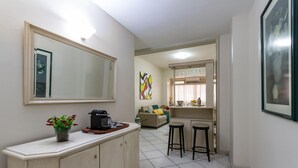 A compact living space with a kitchenette, a dining area with stools, a sofa, and a large mirror. - 2 Minutes From Copacabana Beach A303 (Rio de Janeiro)