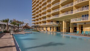 Ein Hotel mit großem Pool, mehreren Balkonen und einem Riesenrad im Hintergrund.