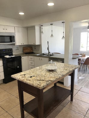 Enjoy cooking in this well-equipped kitchen with a granite countertop, white cabinets, and a black stove.