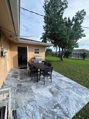 Enjoy al fresco dining on the patio, surrounded by a beautifully manicured lawn and a tree.